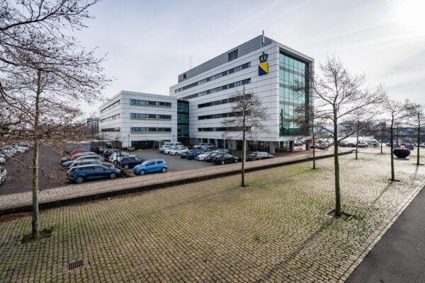 Modern kantoorgebouw aan de Waalhaven O.Z. in Rotterdam met parkeerplaats en omliggende bomen.